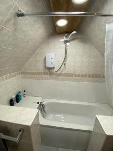 a bathroom with a bath tub with a shower at Pet Friendly Dairy Cottage in Solihull