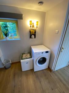 a laundry room with a washing machine and a window at Pet Friendly Dairy Cottage in Solihull