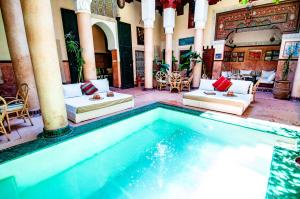 a swimming pool in a building with couches and chairs at Riad Chorfa in Marrakech