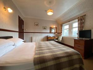 um quarto com uma cama, uma secretária e uma televisão em Kings Arms Hotel em Lockerbie