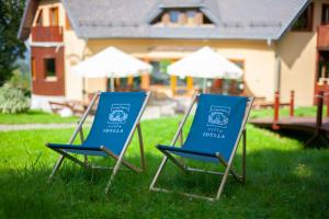 deux chaises bleues assises dans l'herbe devant une maison dans l'établissement Villa Idylla, à Przesieka
