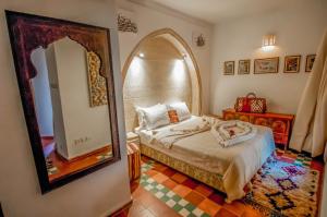 a room with a bed, a mirror and a painting on the wall at Riad Chorfa in Marrakesh