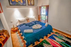 a bedroom with a bed with a blue blanket and a rug at Riad Chorfa in Marrakesh
