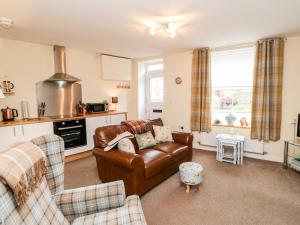 a living room with a leather couch and a kitchen at October Cottage in Crook