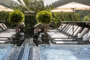 una piscina con sillas y sombrillas junto a una piscina en Hotel Gappmaier en Saalbach Hinterglemm