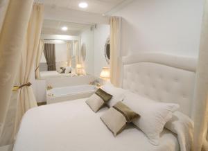 a white bedroom with a bed and a bath tub at Apartamento Romero Garden B in Villanueva de Arosa