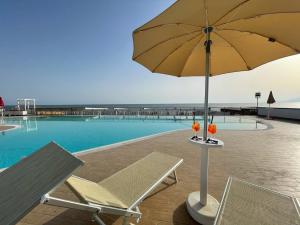 蓬泰卡尼亞諾法伊阿諾的住宿－Blu Hotel，一个带椅子和遮阳伞的游泳池,旁边是一张桌子