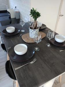 uma mesa de madeira com pratos e copos e uma planta sobre ela em L'annexe em Courseulles-sur-Mer