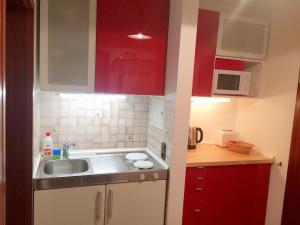 een kleine keuken met rode kasten en een spoelbak bij Gschwendtnerhof App5 Pätzig in Aschau im Chiemgau +34 foto's
