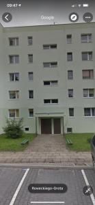 a large white building with a parking lot in front of it at Shutter Apartment in Gorzów Wielkopolski
