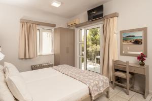 a bedroom with a white bed and a balcony at Niriis Hotel in Kato Daratso