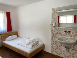 a bathroom with a bed and a sink at Berggasthaus Piz Calmot in Andermatt