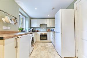 una cucina con armadietti bianchi e frigorifero bianco di Host & Stay - Percy Cottage a Otterburn