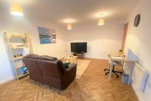 a living room with a couch and a desk and a television at The Onyx Suite - 1 Bed apartment w/ free parking in Cardiff