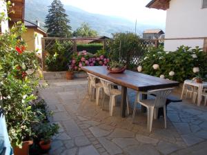 a wooden table and chairs on a patio with flowers at Les Hirondelles in Fenis