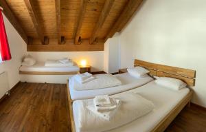 two beds in a room with a wooden ceiling at Berggasthaus Piz Calmot in Andermatt