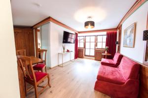 ein Wohnzimmer mit einem roten Sofa und Stühlen in der Unterkunft Hotel San Marco in Füssen