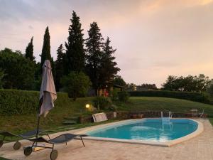 a swimming pool with an umbrella next to a yard at Villa Bellavista - Piscina ad uso esclusivo in Celle sul Rigo