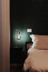 een slaapkamer met een groene muur met een bed en een lamp bij Casa LiLu by Comorooms in Como