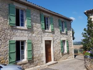 uma casa de pedra com persianas verdes e uma porta em La Capèra em Lachapelle