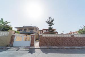 a brick fence with a white gate and a house at Expoholidays-Chalet Bahari primera linea de playa in Roquetas de Mar