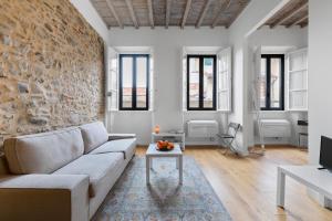 - un salon avec un canapé blanc et un mur en pierre dans l'établissement Teatro della Pergola Apartment, à Florence