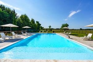 una gran piscina con sillas y sombrillas en La Scuderia Casa Vacanze, en San Zeno