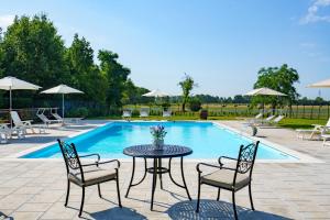 un patio con mesa, sillas y piscina en La Scuderia Casa Vacanze, en San Zeno