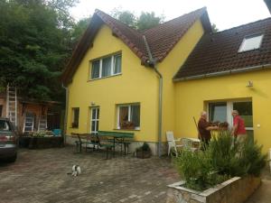 duas pessoas à porta de uma casa amarela em Foki Vendégház em Hidegség