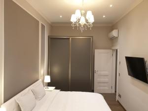 a bedroom with a white bed and a chandelier at MARBEO 5 Star Luxury Suites - Peldu in Liepāja