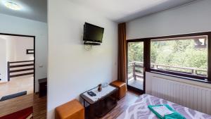 a room with a bed and a tv and a window at Perla Sarisorului in Sărişor