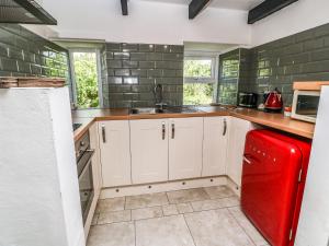 a kitchen with white cabinets and a red refrigerator at Blackberry Cottage in Carbis Bay