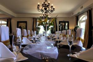 a dining room with a long table with chairs and a chandelier at Merci Hotel in Galanta