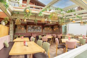 ein Restaurant mit Holztischen, Stühlen und Pflanzen in der Unterkunft Hotel San Marco in Füssen