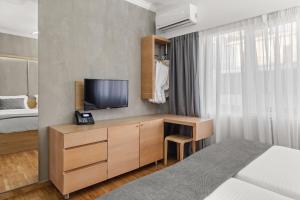 a bedroom with a bed and a desk with a television at Athens Warehouse Boutique Hotel & Suites in Athens