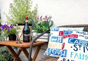 una botella de vino en una mesa con una almohada y vasos en The Studio, en Callington