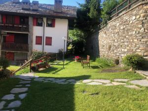 a house with a stone wall and a bench in the yard at Belle Vue #Bluchalet in Courmayeur