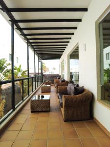 a screened porch with couches and tables on a balcony at Hotel Pocillos Playa, solo Adultos in Puerto del Carmen
