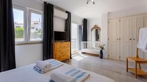 a bedroom with a bed and a tv and windows at 3 Bed Holiday Home Lakeside Village Quinta Do Lago in Faro