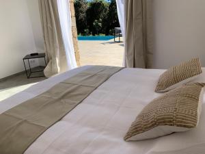 a white bed with pillows and a view of a pool at DOMAINE NAPOLEON CORSICA FIGARI in Figari