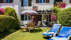eine Terrasse mit Stühlen, einem Tisch und einem Sonnenschirm in der Unterkunft 3 Bed Holiday Home Lakeside Village Quinta Do Lago in Faro