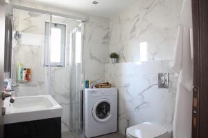a white bathroom with a washing machine and a sink at Edem Beach Apartment with Sea View by Athenian Homes in Athens