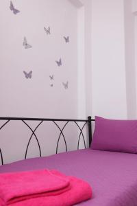 un letto con lenzuola viola e farfalle sul muro di Luxury Villas Polychrono a Polykhrono