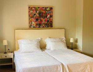 two beds in a bedroom with a painting on the wall at Rex Hotel - Bebeka's in Zakharo