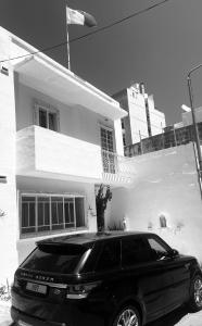 une voiture noire garée devant une maison blanche dans l'établissement Ave Maria Guest House, à San Ġiljan