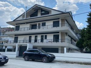 um carro preto estacionado em frente a um edifício branco em Ioannina Luxury Suites & Apartments em Ioannina