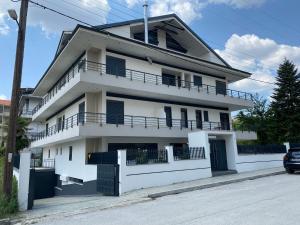 ein weißes Haus mit Balkon auf einer Straße in der Unterkunft Ioannina Luxury Suites & Apartments in Ioannina