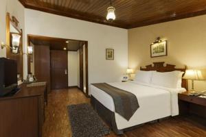 a hotel room with a large bed and a large window at The Naini Retreat, Nainital by Leisure Hotels in Nainital
