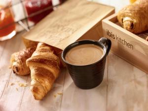 a cup of coffee sitting next to a box of croissants at ibis Fortaleza Centro de Eventos in Fortaleza