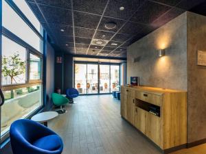 a office with a blue chair and a large window at ibis budget Huerta De Murcia in Murcia